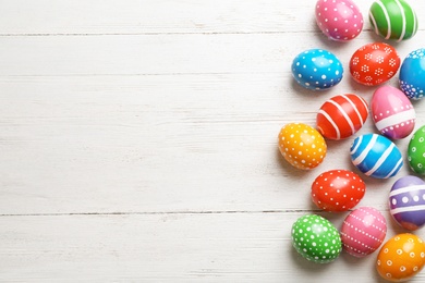 Photo of Decorated Easter eggs and space for text on wooden background, top view
