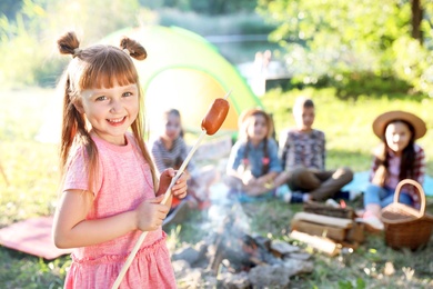 Photo of Little girl with fried sausage outdoors. Summer camp