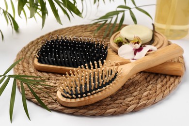Photo of Wooden hairbrushes, solid shampoo, orchid flowers and leaves on white background