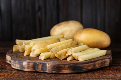 Photo of Whole and cut raw potatoes on wooden table, closeup