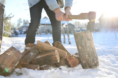 Photo of Man chopping wood with axe outdoors on winter day, closeup