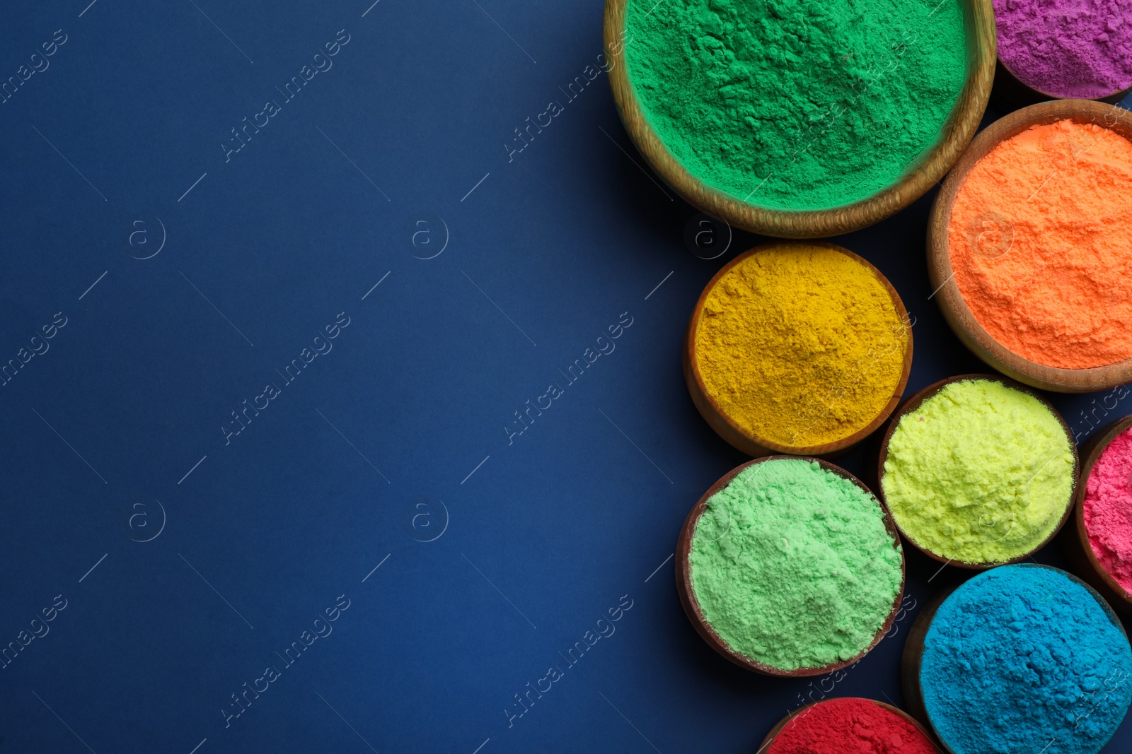 Photo of Colorful powders in bowls on blue background, flat lay with space for text. Holi festival celebration