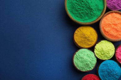 Photo of Colorful powders in bowls on blue background, flat lay with space for text. Holi festival celebration