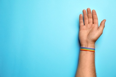 Man with rainbow ribbon on blue background, top view and space for text. Gay symbol