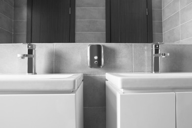 Photo of Beautiful clean sinks near mirror in public toilet