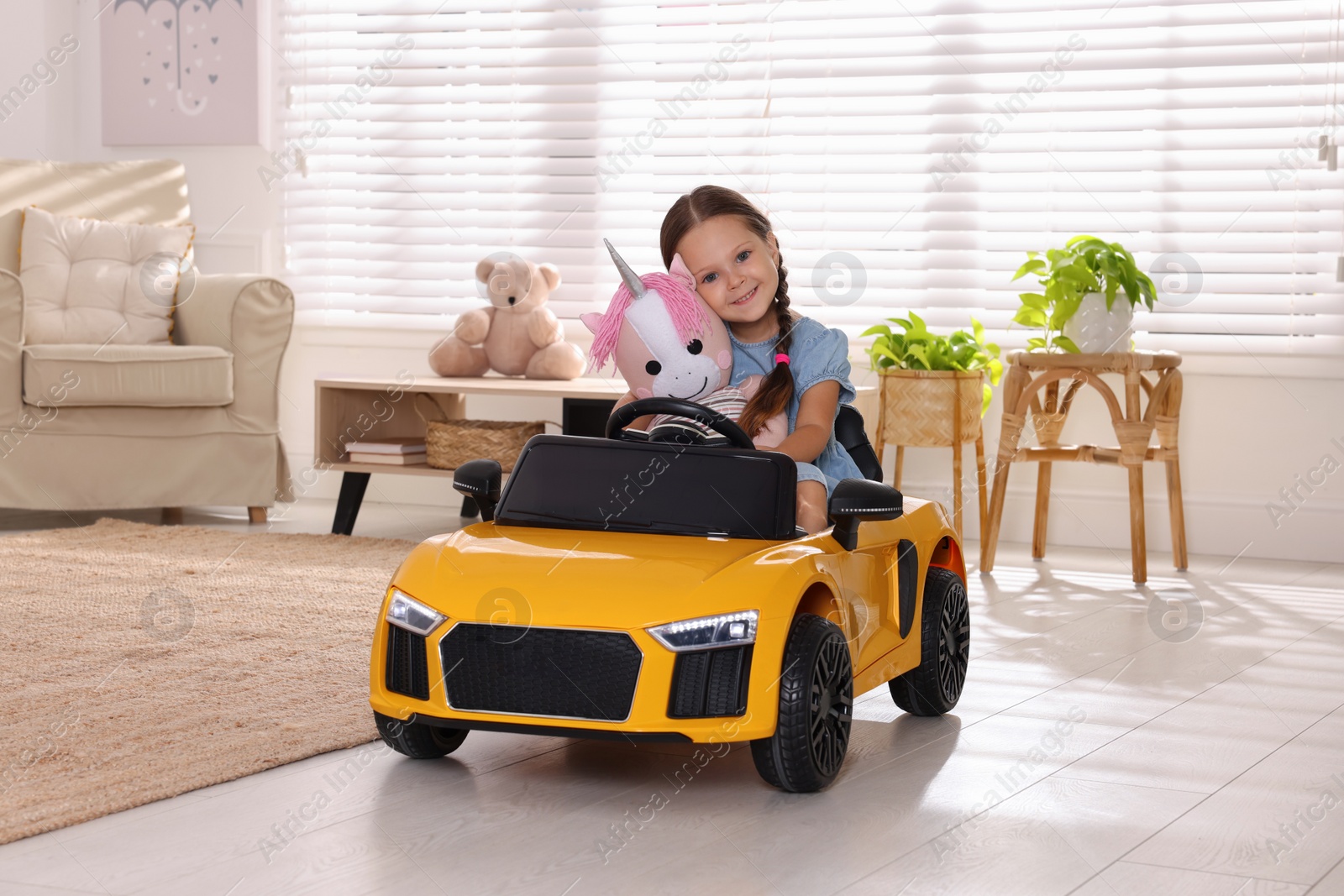 Photo of Adorable child with toy driving car in room at home