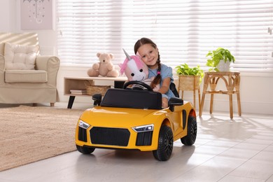 Adorable child with toy driving car in room at home