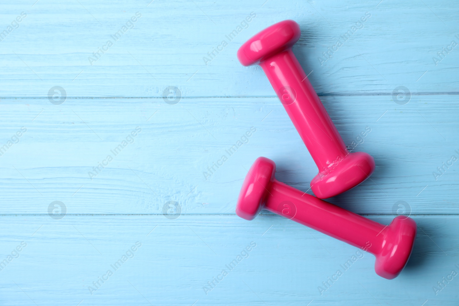 Photo of Bright dumbbells and space for text on wooden background, flat lay. Home fitness