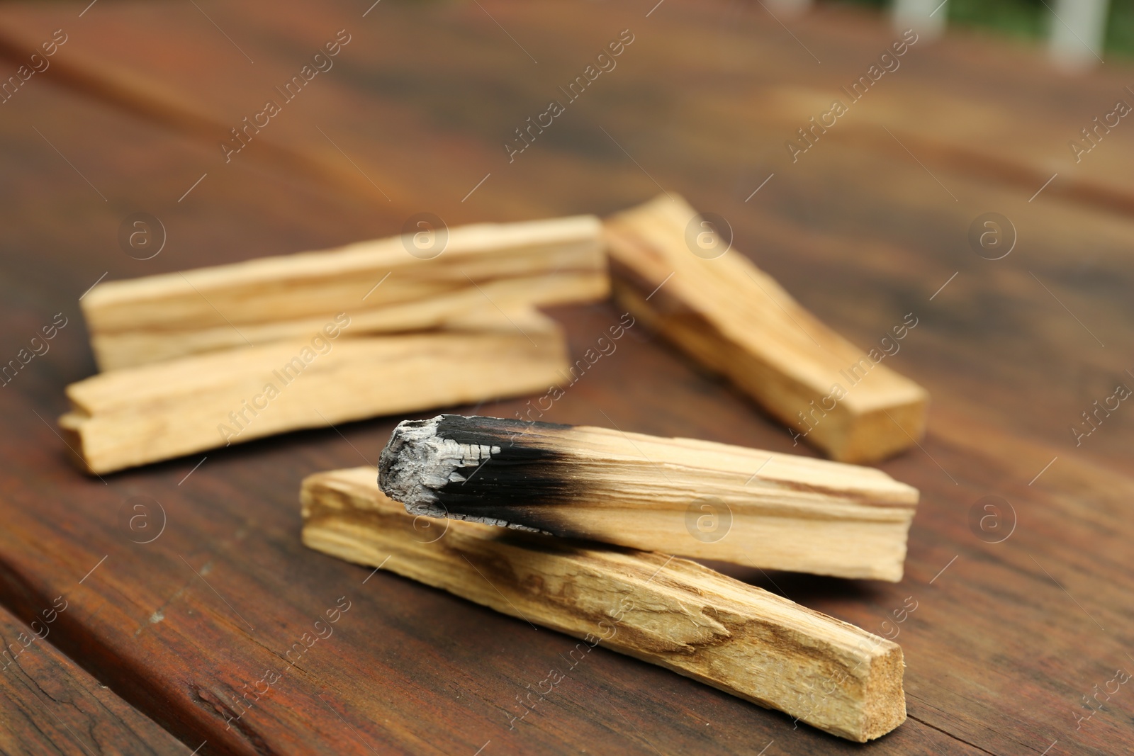 Photo of Palo Santo stick smoldering on wooden table, closeup