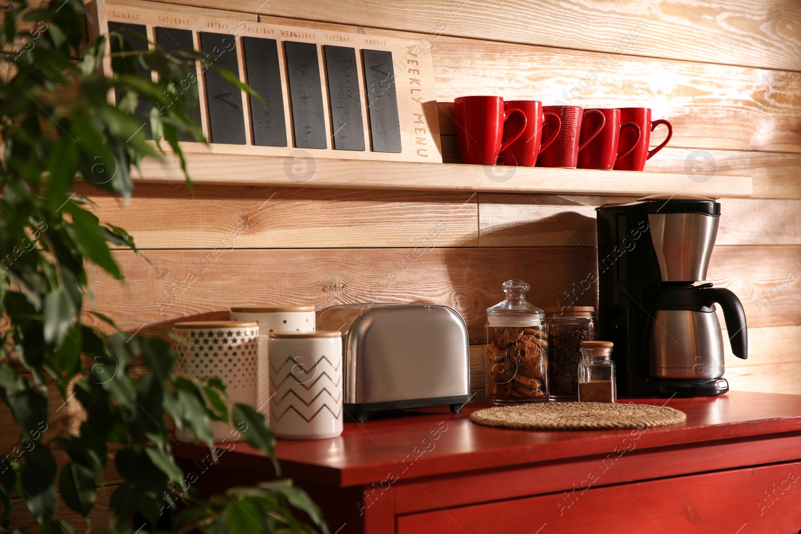 Photo of Stylish room interior with modern coffeemaker and toaster on red chest of drawers