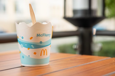 WARSAW, POLAND - SEPTEMBER 04, 2022: McDonald's ice cream on wooden table outdoors, space for text