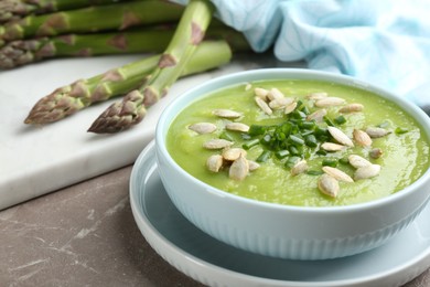 Delicious asparagus soup in bowl on grey marble table