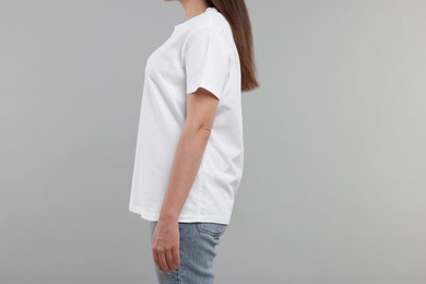 Photo of Woman in white t-shirt on grey background, closeup