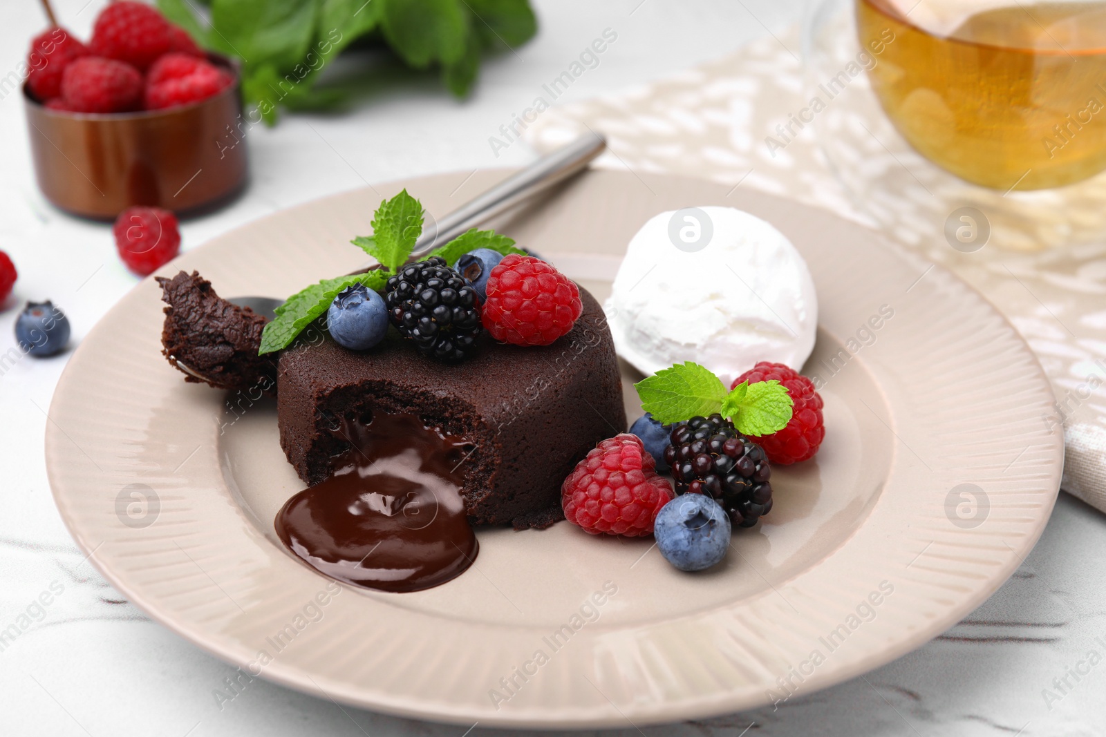 Photo of Delicious chocolate fondant served with fresh berries and ice cream on white table, closeup