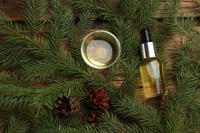 Photo of Pine essential oil, cones and branches on wooden table, flat lay