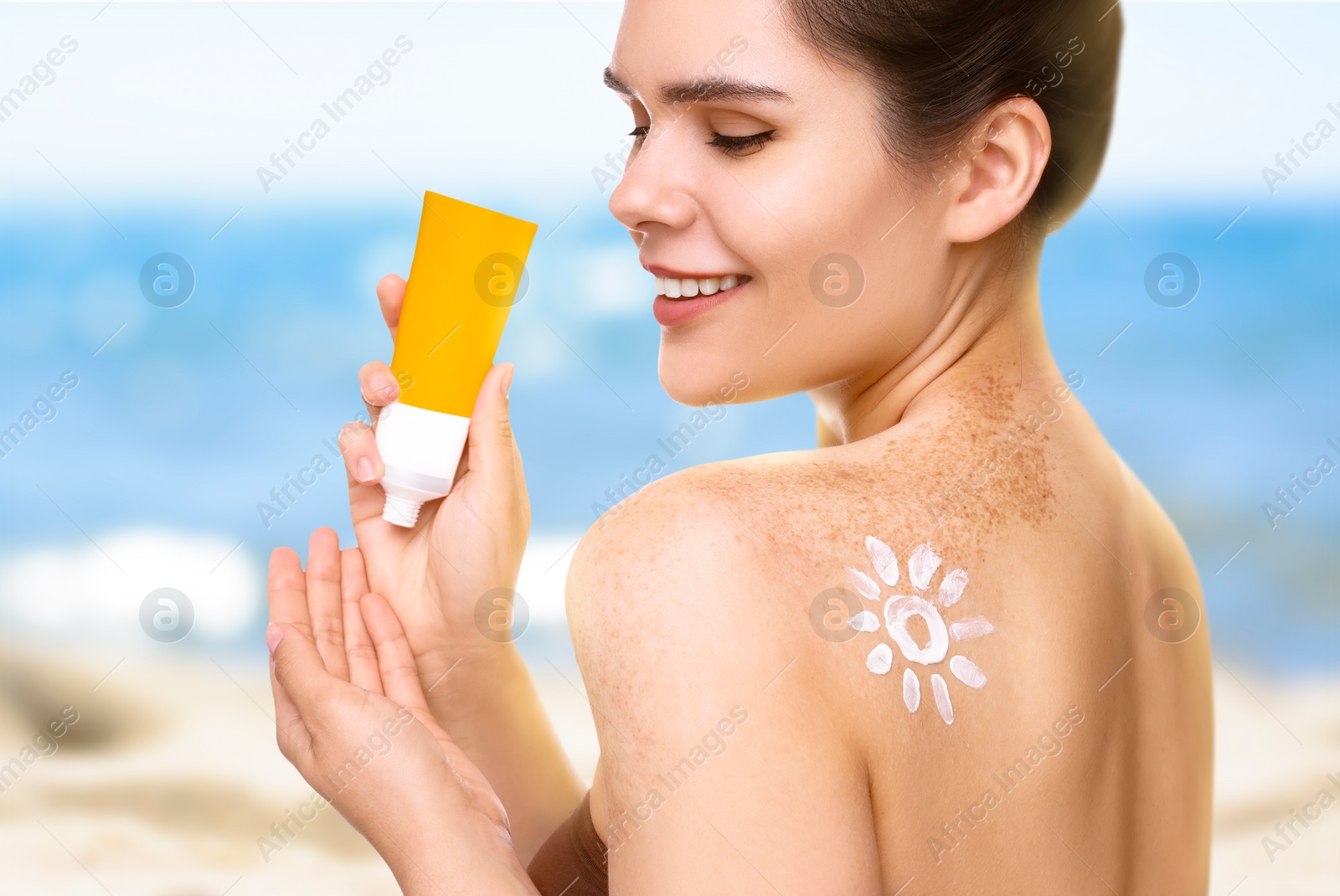 Image of Sun protection. Beautiful young woman with tube of sunblock on beach, closeup