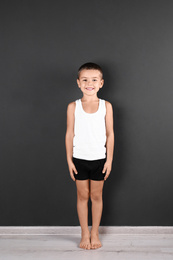 Photo of Cute little boy in underwear near dark wall