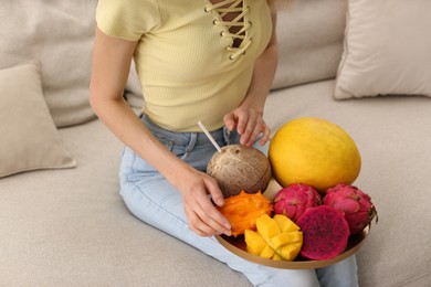 Young woman with fresh exotic fruits on sofa, closeup