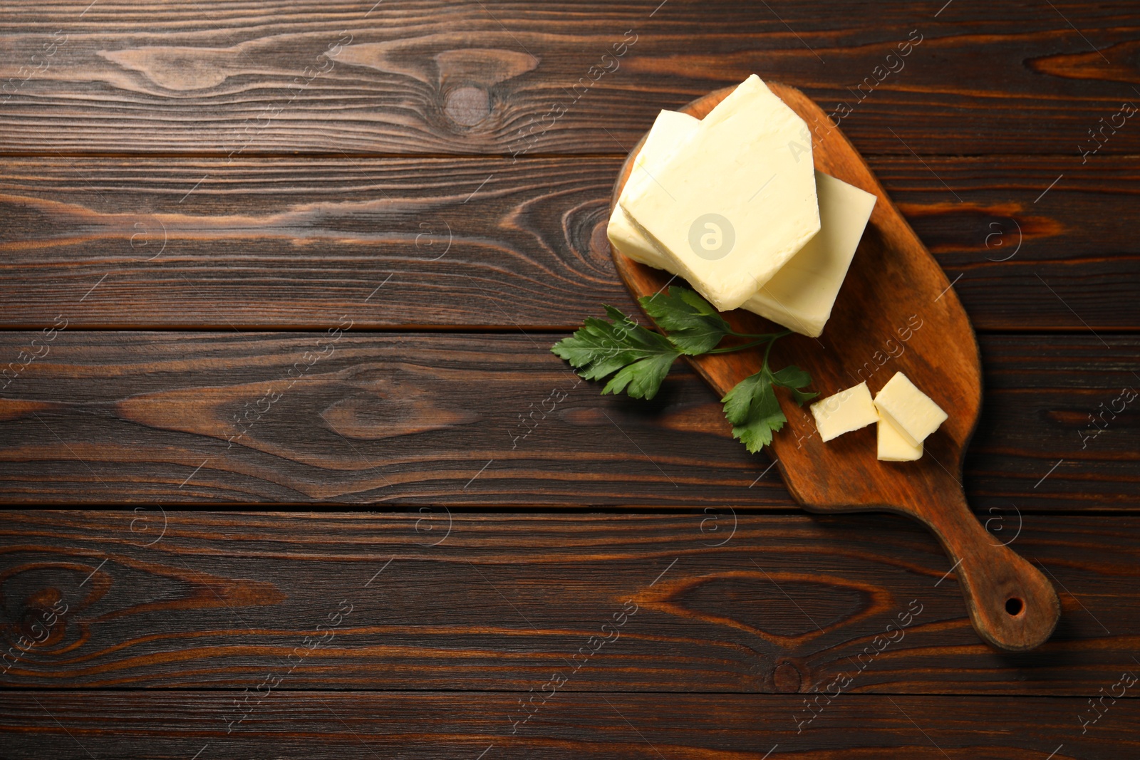 Photo of Tasty butter and parsley on wooden table, top view. Space for text