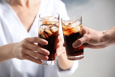 Photo of Friends with glasses of cold cola on color background, closeup