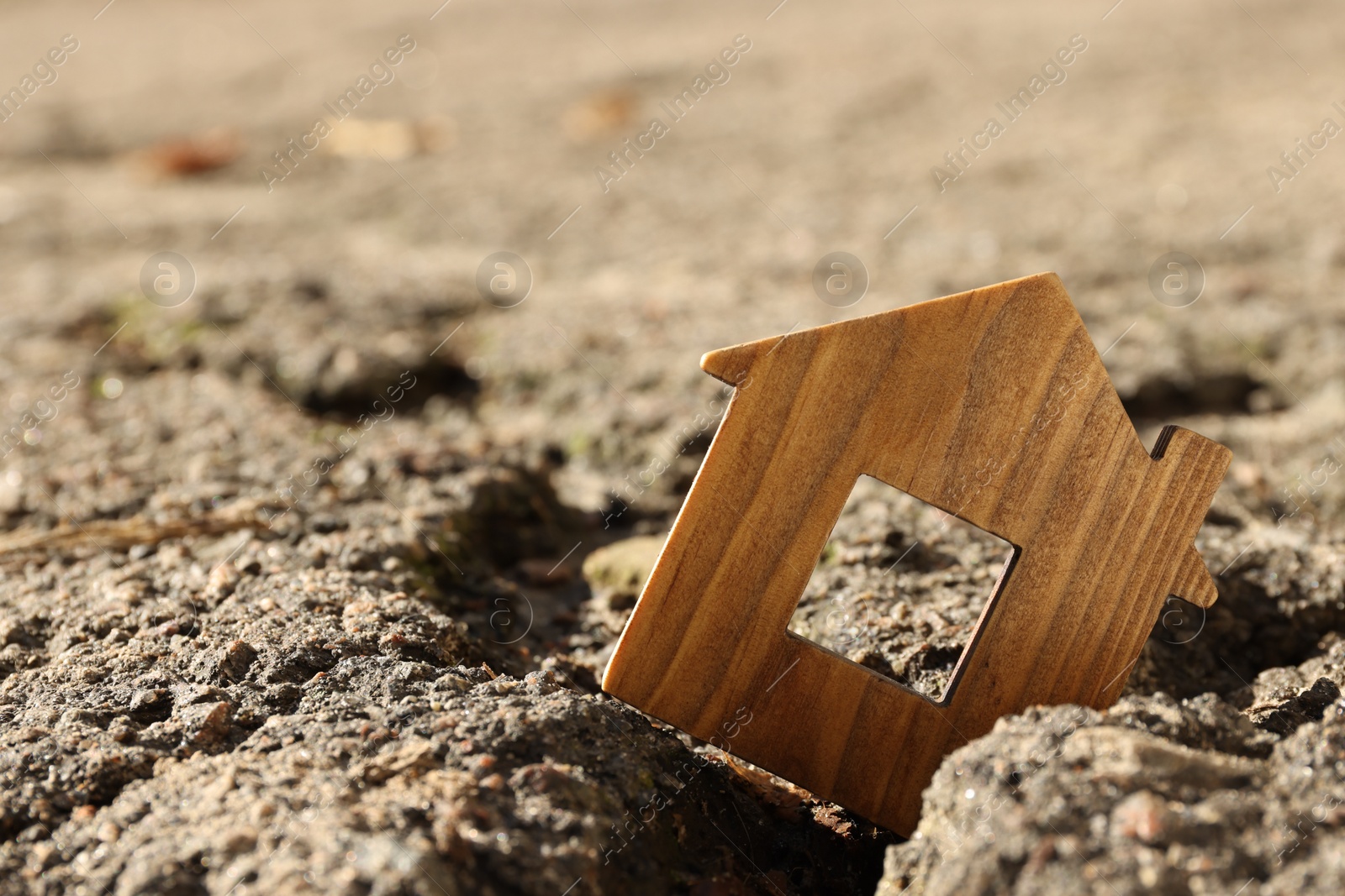 Photo of Wooden house model in cracked asphalt. Earthquake disaster