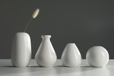 Photo of Different stylish vases and dry flower on white table