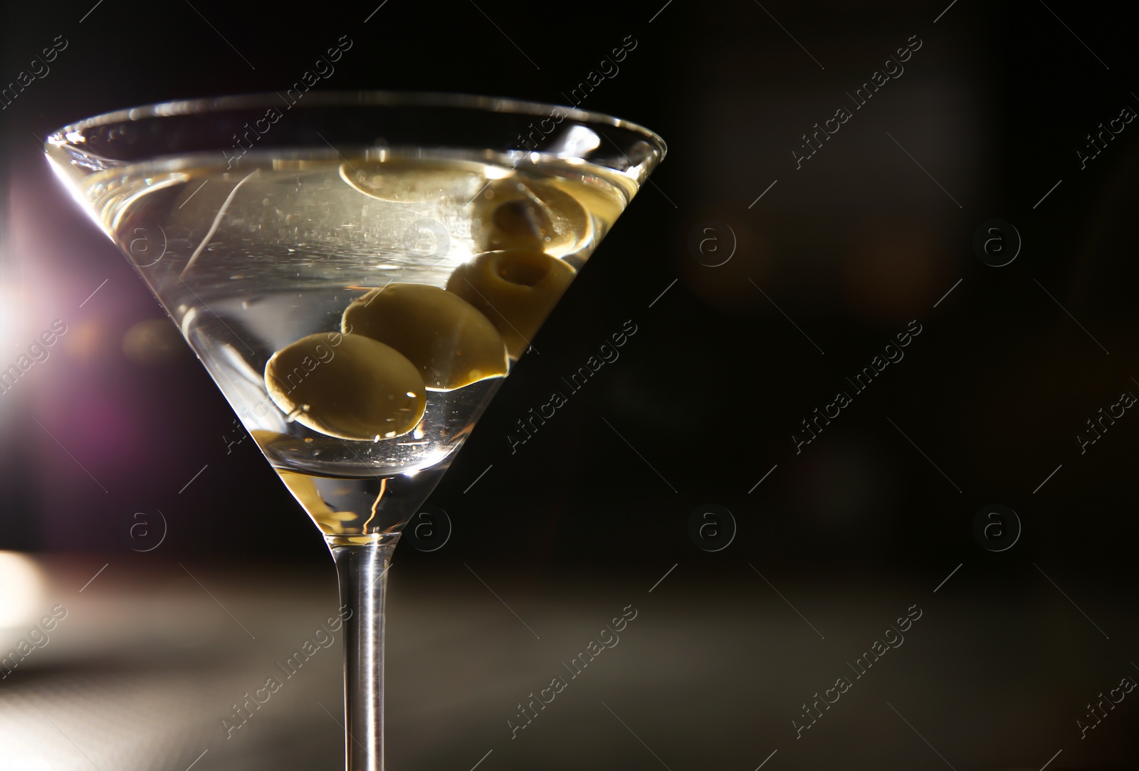 Photo of Glass of martini with olives in bar, closeup. Space for text