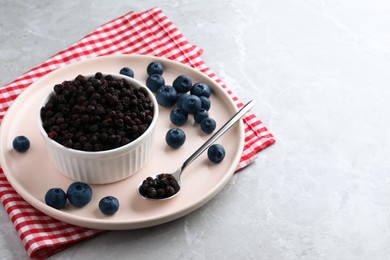 Photo of Freeze dried and fresh blueberries on light grey table. Space for text