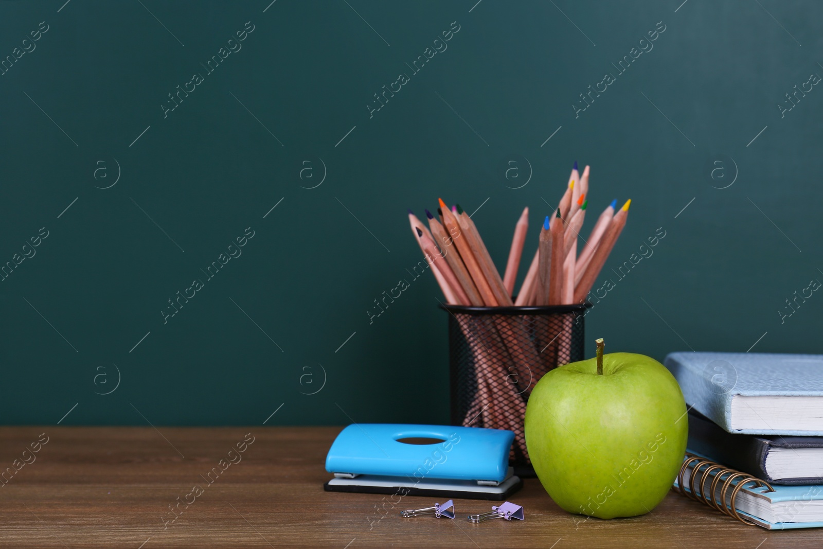 Photo of Composition with stationery and apple on table near chalkboard, space for text. Doing homework