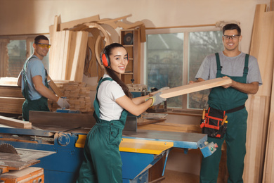 Photo of Professional carpenters with wooden plank in workshop