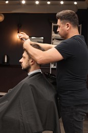 Photo of Professional hairdresser cutting man's hair in barbershop