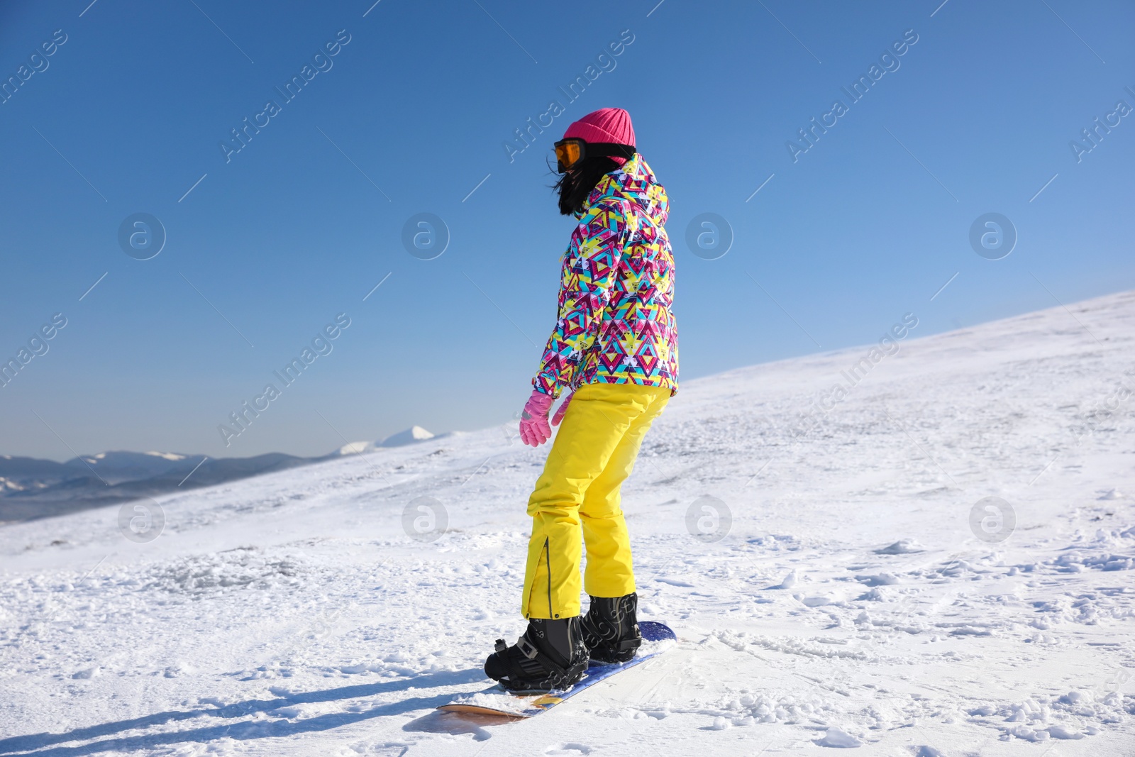 Photo of Young woman snowboarding on hill. Winter vacation