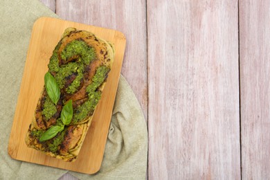 Photo of Freshly baked pesto bread with basil on wooden table, top view. Space for text