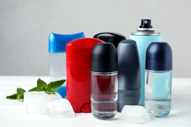 Photo of Natural male roll-on deodorants with ice and mint on white table