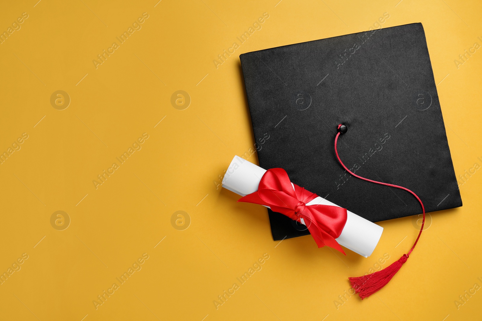 Photo of Graduation hat and diploma on yellow background, flat lay. Space for text