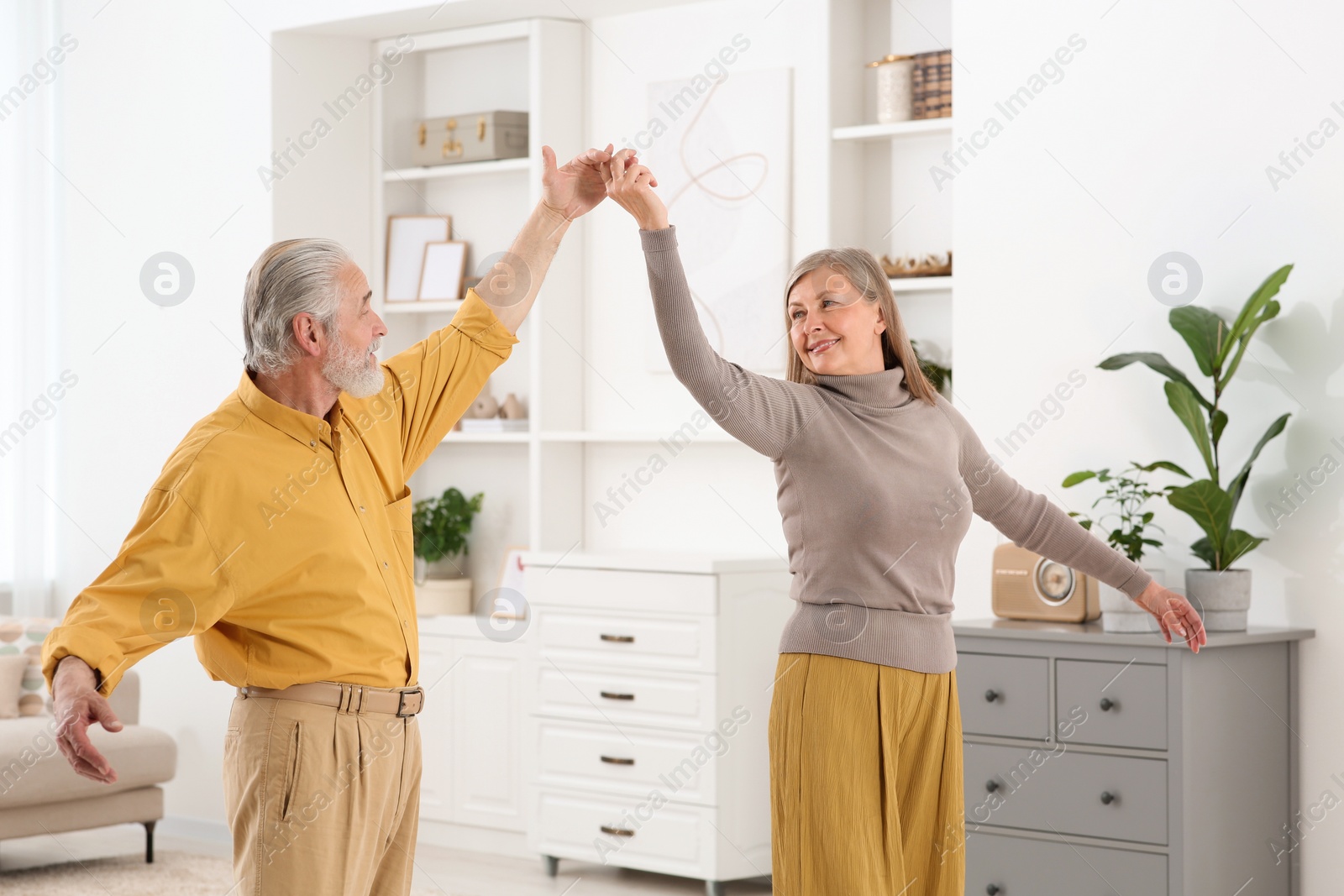 Photo of Affectionate senior couple dancing in living room at home