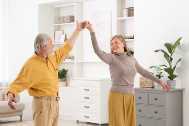 Photo of Affectionate senior couple dancing in living room at home