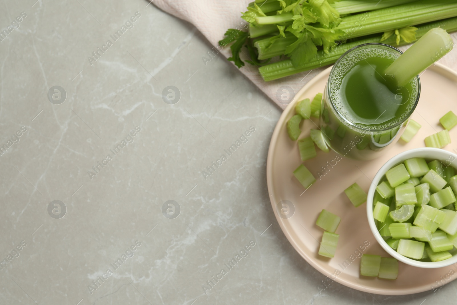 Photo of Glass of delicious celery juice and vegetables on grey table, flat lay. Space for text
