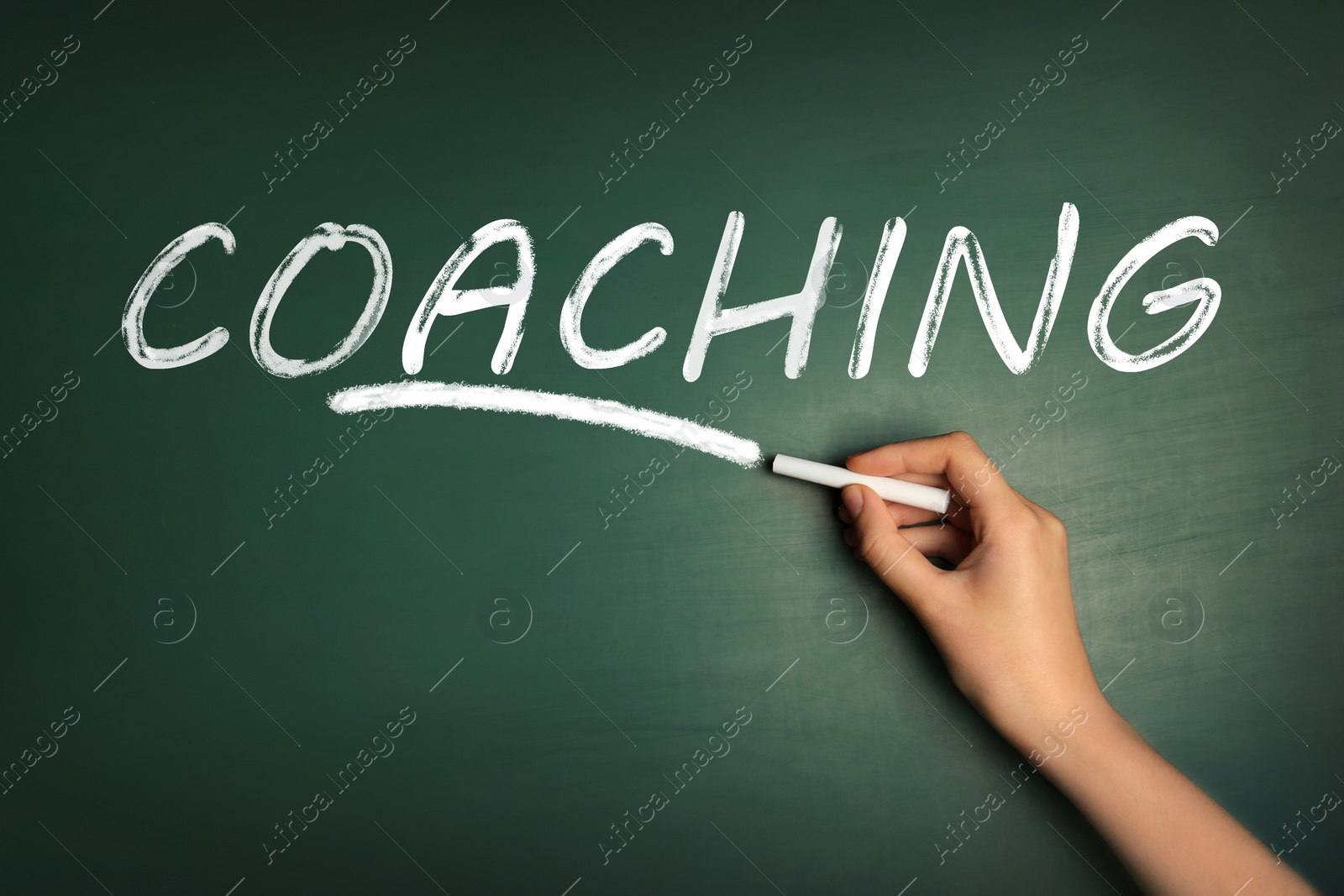 Image of Adult learning. Woman writing word COACHING on green chalkboard, closeup