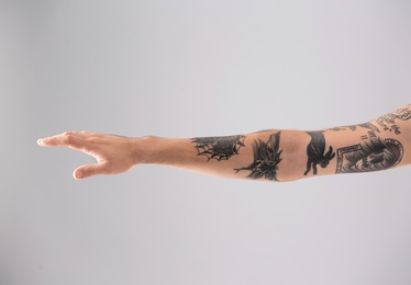 Man's arm with stylish tattoos on grey background