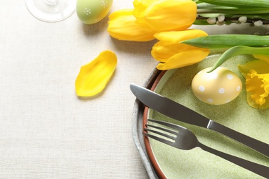 Photo of Festive Easter table setting with flowers on light background, top view. Space for text