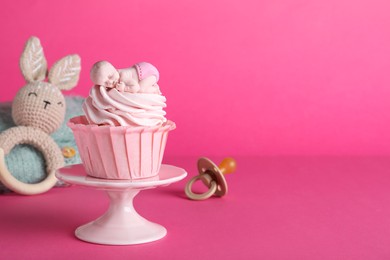 Beautifully decorated baby shower cupcake with cream and girl topper on pink background. Space for text