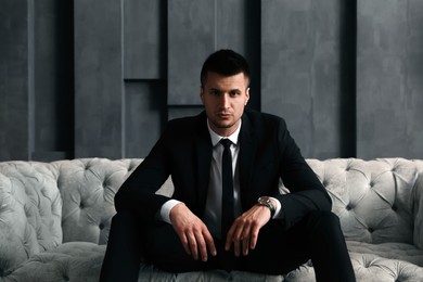 Photo of Handsome businessman on sofa indoors. Luxury lifestyle