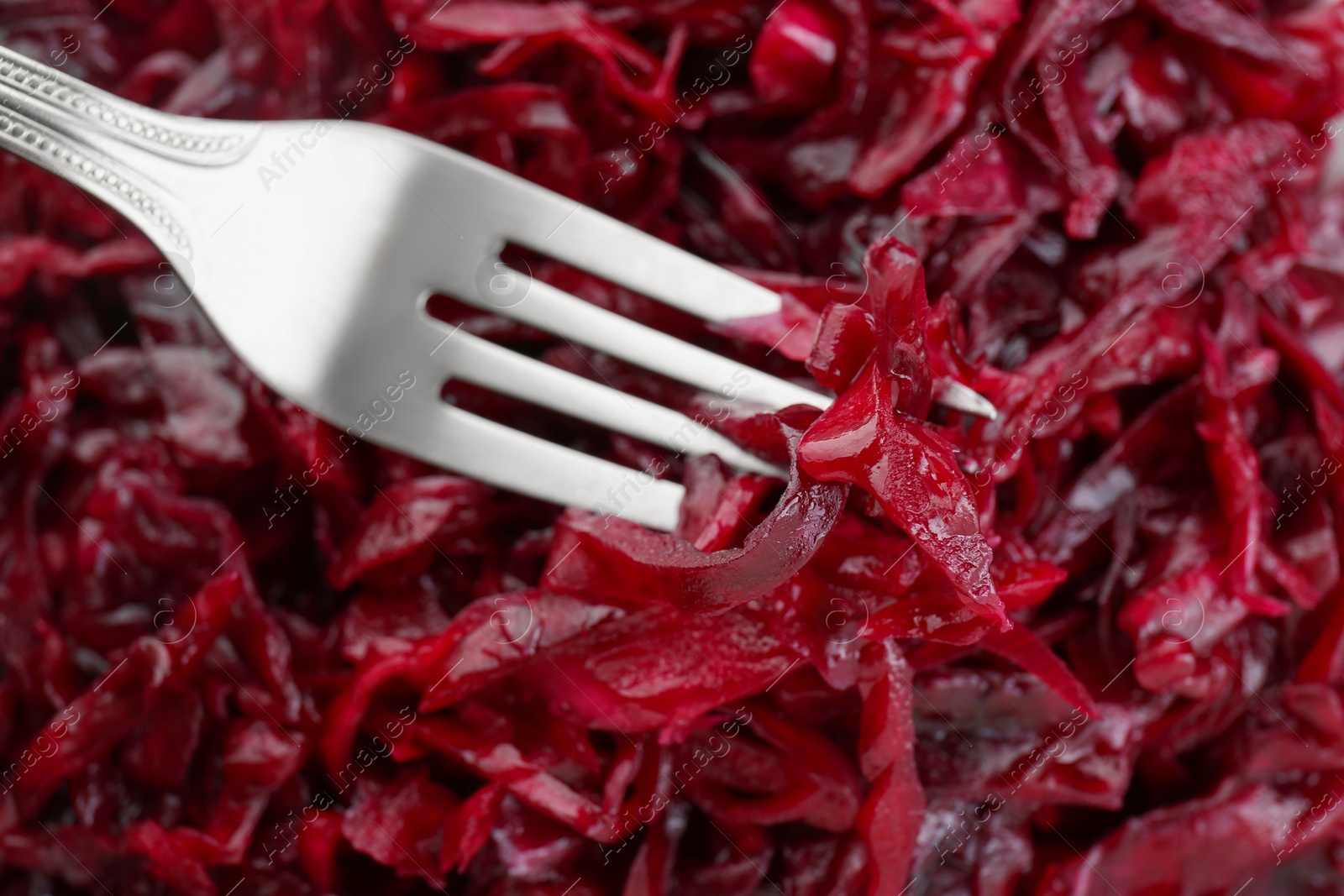 Photo of Fork with tasty red cabbage sauerkraut as background, closeup