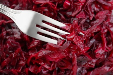 Fork with tasty red cabbage sauerkraut as background, closeup