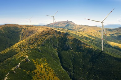 Modern wind turbines in mountains on sunny day. Alternative energy source