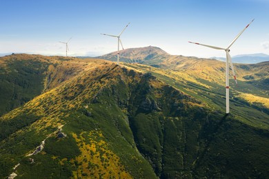 Image of Modern wind turbines in mountains on sunny day. Alternative energy source