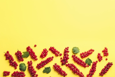 Delicious red currants and leaves on yellow background, flat lay. Space for text