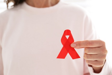 Photo of Woman holding red awareness ribbon, closeup with space for text. World AIDS disease day