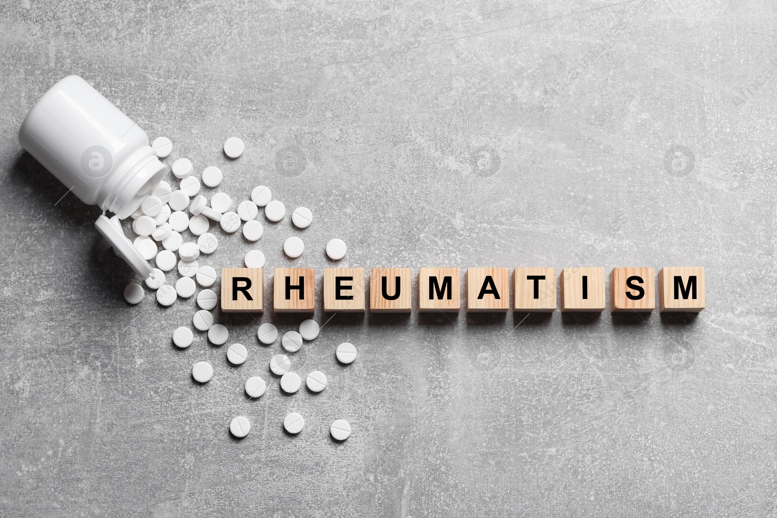 Photo of Word Rheumatism made of cubes and pills on light gray textured background, flat lay